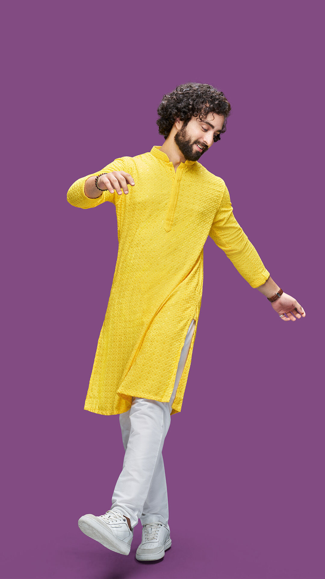Young man in a yellow embroidered kurta styled with white trousers and sneakers, showcasing a modern festive kurta look.